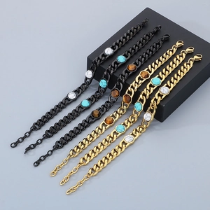 Detail of gold and black cuban chain bracelets with turquoise and marble stone inlays