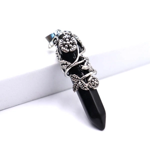 Détail d'un pendentif hexagonal en obsidienne noire avec motif floral argenté vintage