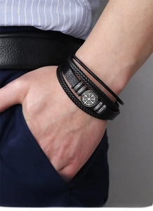 Close-up of a men's layered black leather bracelet featuring a silver Viking compass charm