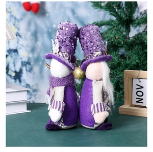 Detail of two Christmas gnomes with purple sequins and long white beards in a snow scene