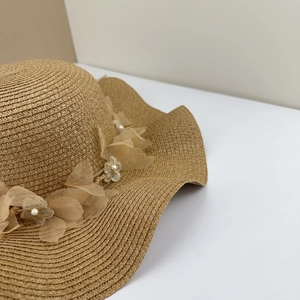 Vue détaillée d'un chapeau de paille pour femme avec fleurs en dentelle et perles