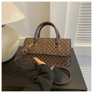 Detailed view of vintage brown patterned handbag with gold hardware and leather handles