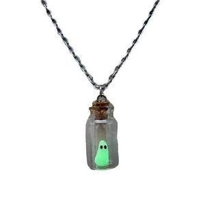 Detail of a glow in the dark green ghost inside a glass bottle pendant with cork