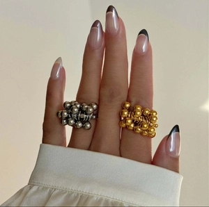 Dettaglio di anelli modulari sferici in oro e argento indossati su una mano
