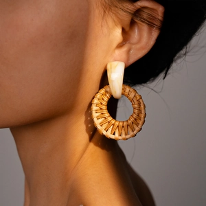 Close-up of geometric resin and woven rattan circular earrings worn on a model