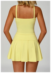 Detail view of the yellow pleated hem and racerback design of the athletic sports dress