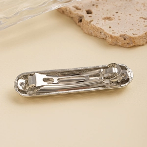 Detail of the silver metal spring hair clip back structure on minimalist background