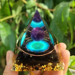 Orgone pyramid with amethyst ball, flower of life pattern and black stones in hand