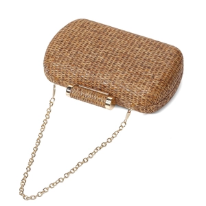 Detail of khaki straw-woven evening clutch with golden metal clasp and chain strap