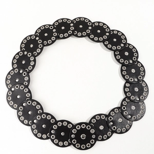 Detailed view of black leather disc belt with silver metal rivets and punk style eyelets