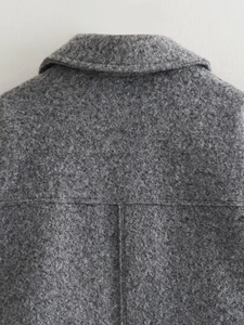 Gros plan sur la texture bouclée grise et les détails du col d'un manteau court