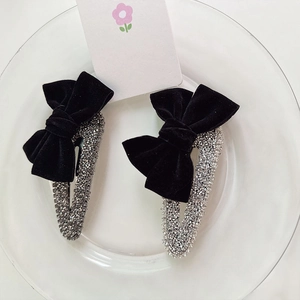Detailed view of black velvet bow hair clips with silver rhinestones on a glass plate