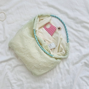 Detail of floral embroidery on green canvas tote with a blue checkered ring handle