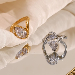 Detailed macro shot of gold and silver teardrop zircon rings on elegant silk background