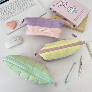 Quilted multi-color stationery bags on desk with brand label and top zipper detail