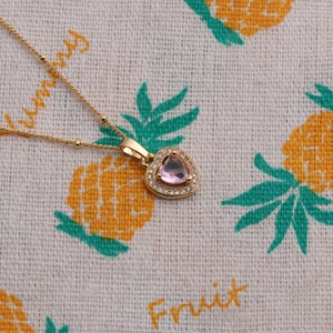 Gros plan du collier pendentif cœur doré avec pierre rose et cristaux brillants