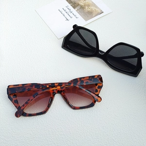 Flat lay of cat-eye sunglasses in black and tortoiseshell finishes on a textured background