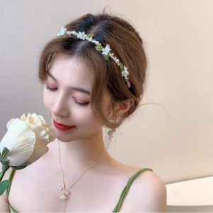 Elegant floral headband with pearls and green leaves on model for forest style look