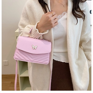 Detail of pink small square bag with V-quilted texture and metal butterfly ornament