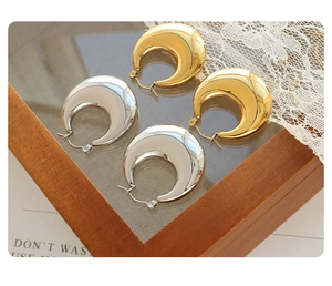 Detailed view of glossy gold and silver U-shaped hoop earrings on elegant background