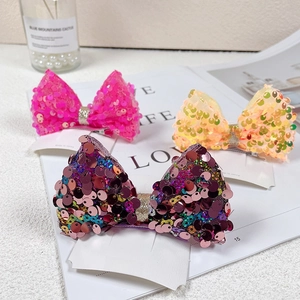 Detail view of sequins mermaid style bow hair clips in pink, yellow, and purple colors