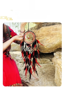 Detailed view of handmade black dream catcher with red beads and natural hanging feathers