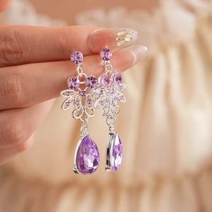Detail of vintage silver earrings with floral hollow design and pear-shaped purple crystals