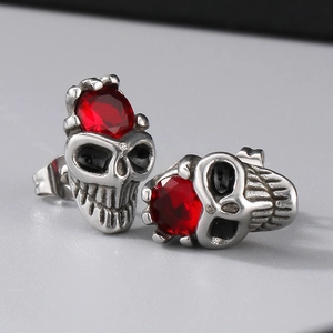 Macro detail of gothic skull stud earrings with red crystal and polished silver finish