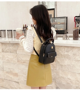 Mini black quilted backpack with gold hardware worn by model in a cafe setting