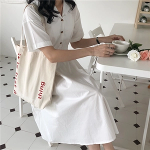 Detailed view of an ivory canvas tote bag paired with a white short sleeve shirt dress
