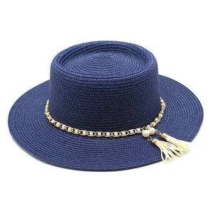 Détail du chapeau canotier bleu foncé avec chaîne dorée, perles et pompons à franges