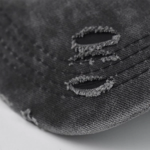 Close-up of distressed vintage grey washed cotton baseball cap with ripped fabric details