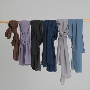 Detailed display of assorted solid color lightweight chiffon scarves hanging on a wooden rod