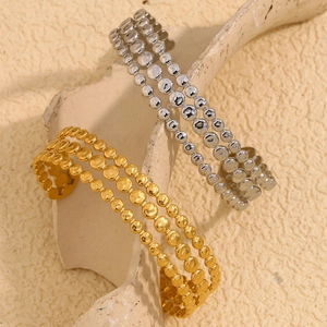 Detailed view of 18K gold and silver layered disc bangles on a ceramic stand