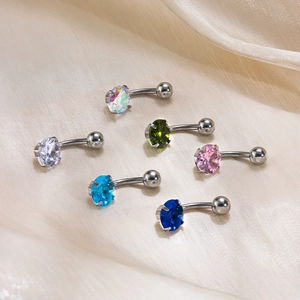 Six assorted belly button rings with colorful zircon gems on beige silk fabric