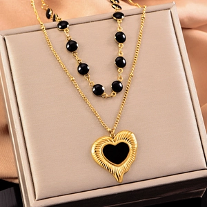 Collier double rang à perles noires et dorées avec pendentif cœur sur présentoir
