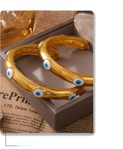 Detail of 18k gold plated evil eye cuff bracelets with blue enamel in a jewelry box