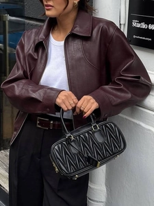 Women's deep burgundy leather bomber jacket and quilted black handbag with gold hardware
