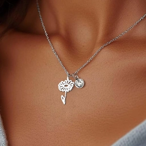 Detail showing a silver daisy charm and a sparkling round zircon on a thin chain necklace