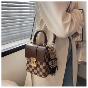 Brown checkered crossbody bag detail with cute bunny charm on a beige coat outfit