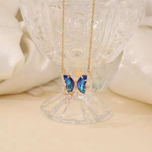 Detail of butterfly pendant necklace with purple crystals and gold chain on glass