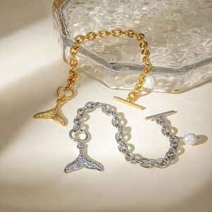 Detail of gold and silver chunky chain bracelets with pearl and fishtail charms