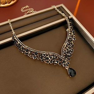 Detail of V-shaped gold necklace with black water drop gemstone in a brown jewelry box