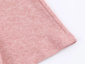 Gros plan détaillé du tissu tricoté rose chiné montrant la texture fine et l'ourlet