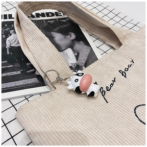 Detail of beige corduroy tote bag with Bear Bear embroidery and cute cow pendant charm