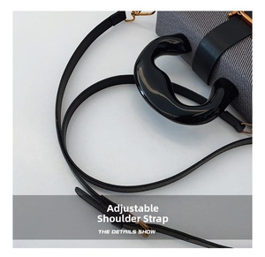 Detail of adjustable leather strap and metal hooks on a modern box bag with purple texture