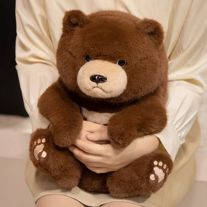 Cute dark brown teddy bear plush toy with soft fur and embroidered paws held by person