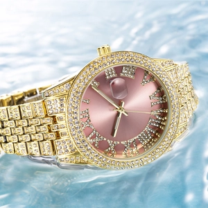 Macro detail of luxury gold watch with pink dial and crystals on sparkling water
