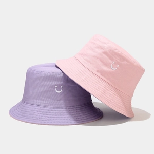 Detail of embroidered smiley face on pink and purple cotton twill bucket hats