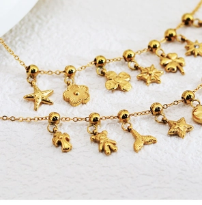 Macro shot of two gold charm bracelets featuring starfish, flower, and bear pendants